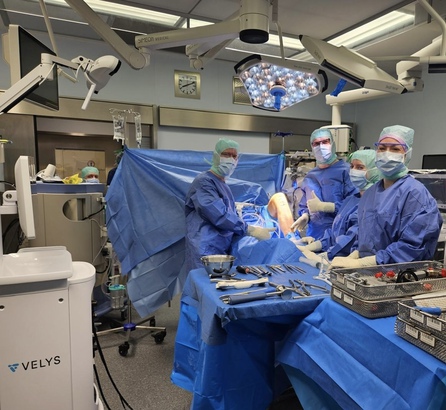 OP-Team während einer Knieoperation im Operationsaal, vier Ärzte und Assistenzkräfte am OP-Tisch