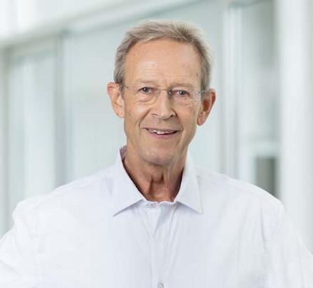 [Translate to Englisch:] Portraitfoto Dr. Alexander Kirgis, lächelnd, weißes Hemd, Arzt der OCM Orthopädische Chirurgie München