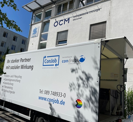 Seitenansicht eines weißen Lkw vor der OCM Praxis in München, die Sonne scheint.